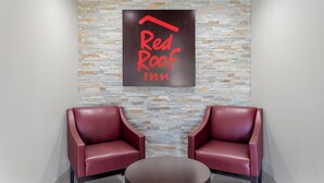 A Red Roof Inn lobby with a stone wall and two red leather chairs. - Red Roof Inn Hope (Hope)