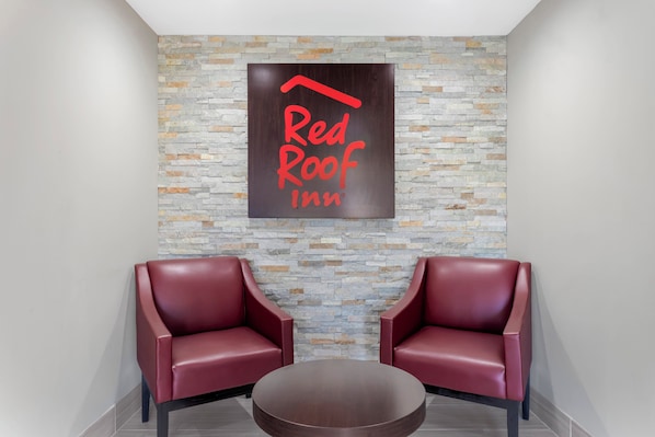 A Red Roof Inn lobby with a stone wall and two red leather chairs. - Red Roof Inn Hope (Hope)
