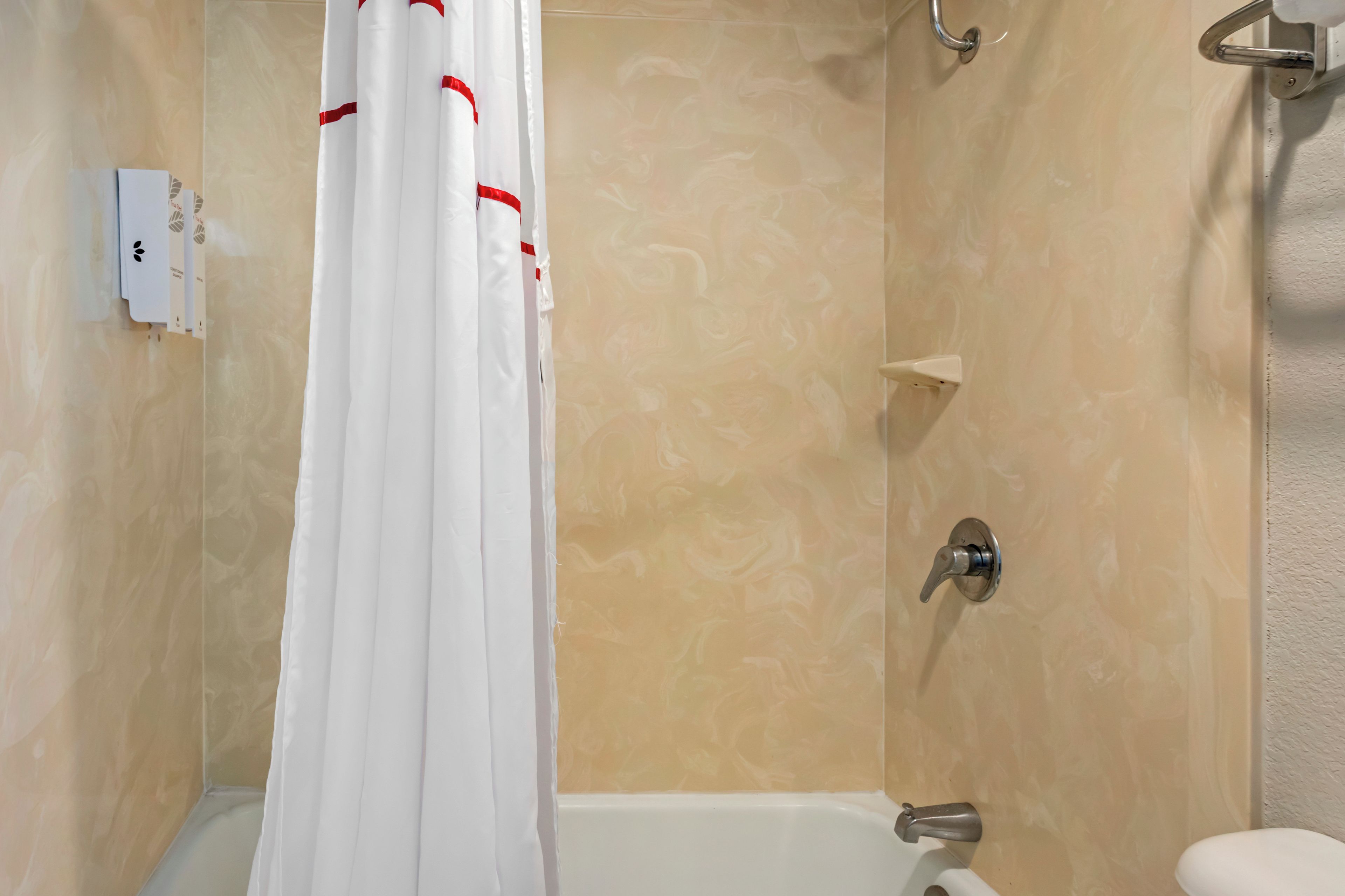 Une salle de bain avec un rideau de douche, une baignoire et des toilettes.