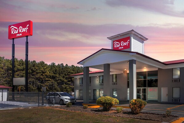 Et Red Roof Inn med moderne design, med et stort skilt, en parkeringsplads og en velplejet græsplæne.
