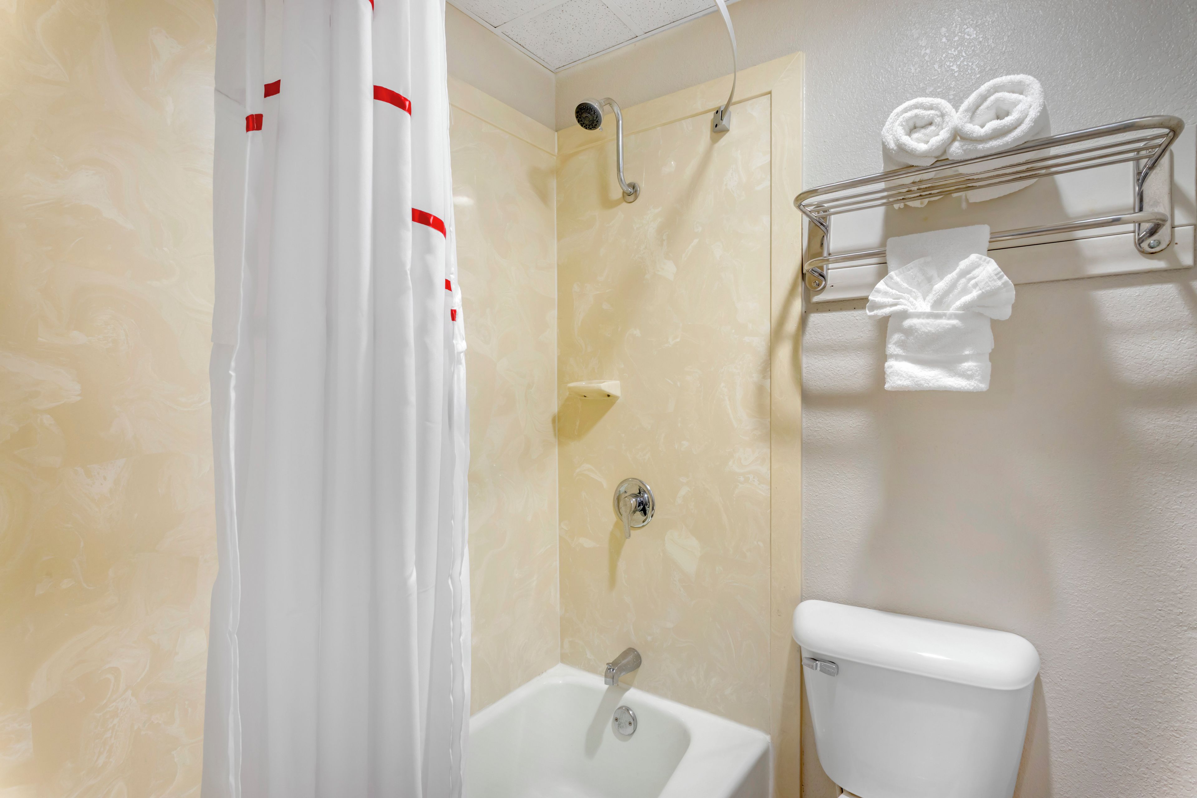 A bathroom with a shower, toilet, and a towel rack.