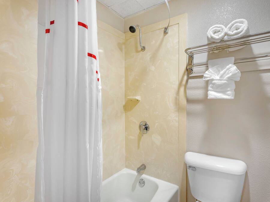 A bathroom with a shower, toilet, and a towel rack.
