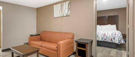 Une chambre d’hôtel avec un canapé, une petite table, une table de chevet et un lit recouvert d’une couvre-lit à motifs.