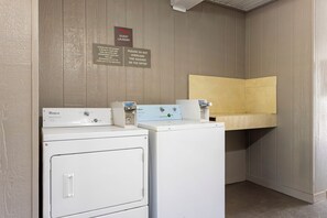 Un área de lavandería con dos lavadoras Whirlpool, un letrero que indica servicio para huéspedes y una advertencia contra sobrecargar las máquinas.