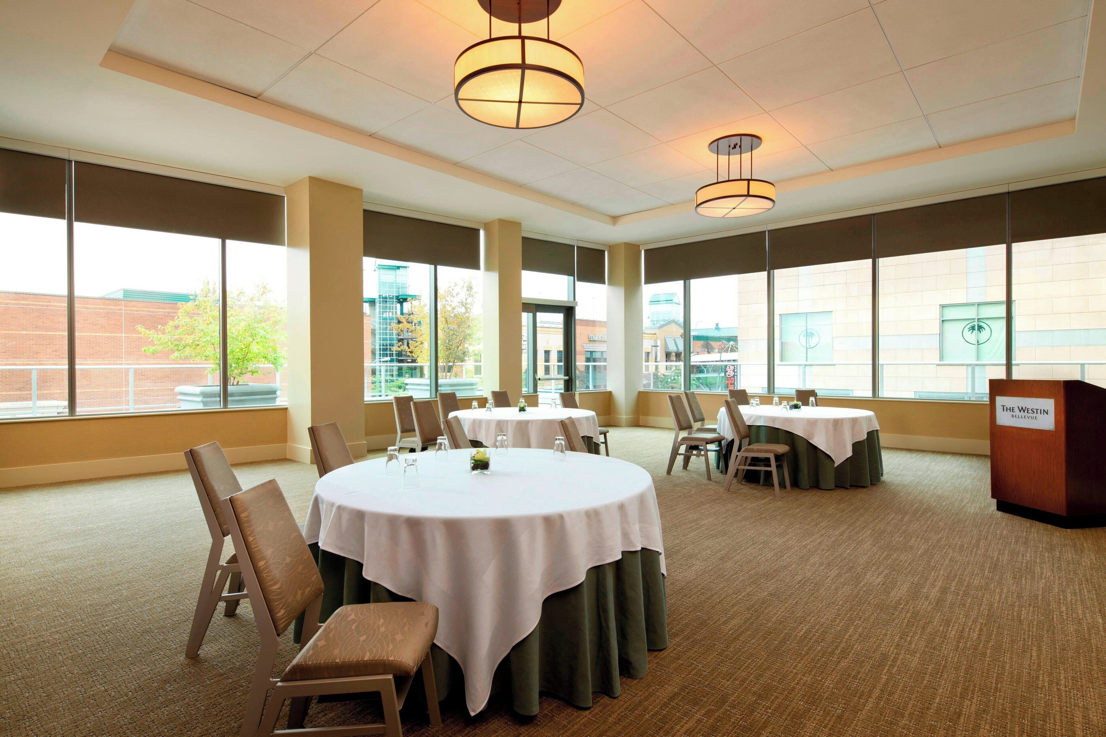A conference room with round tables, chairs, and a podium labeled "The Westin."