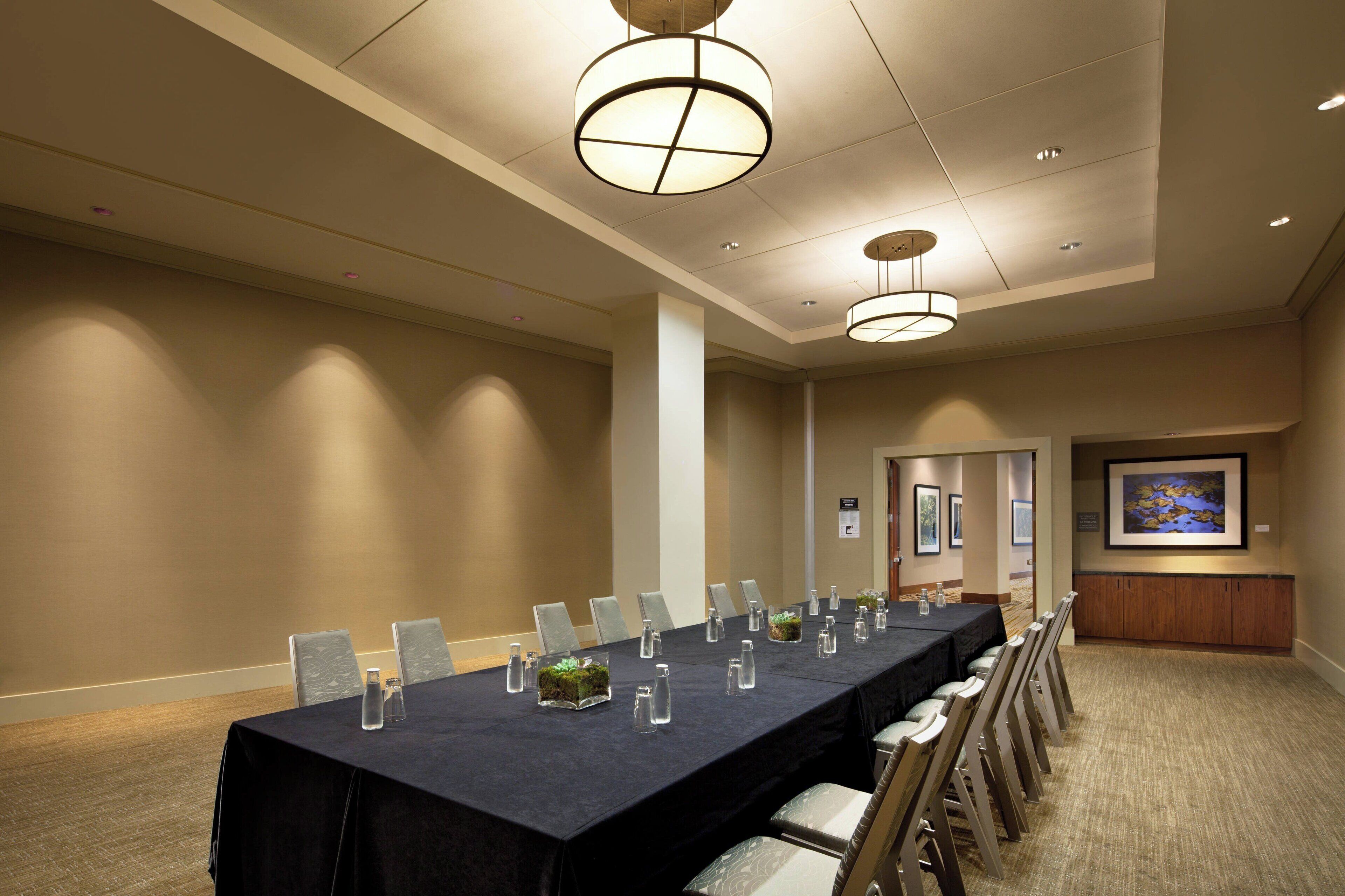 A conference room with a long table, chairs, and a painting on the wall.