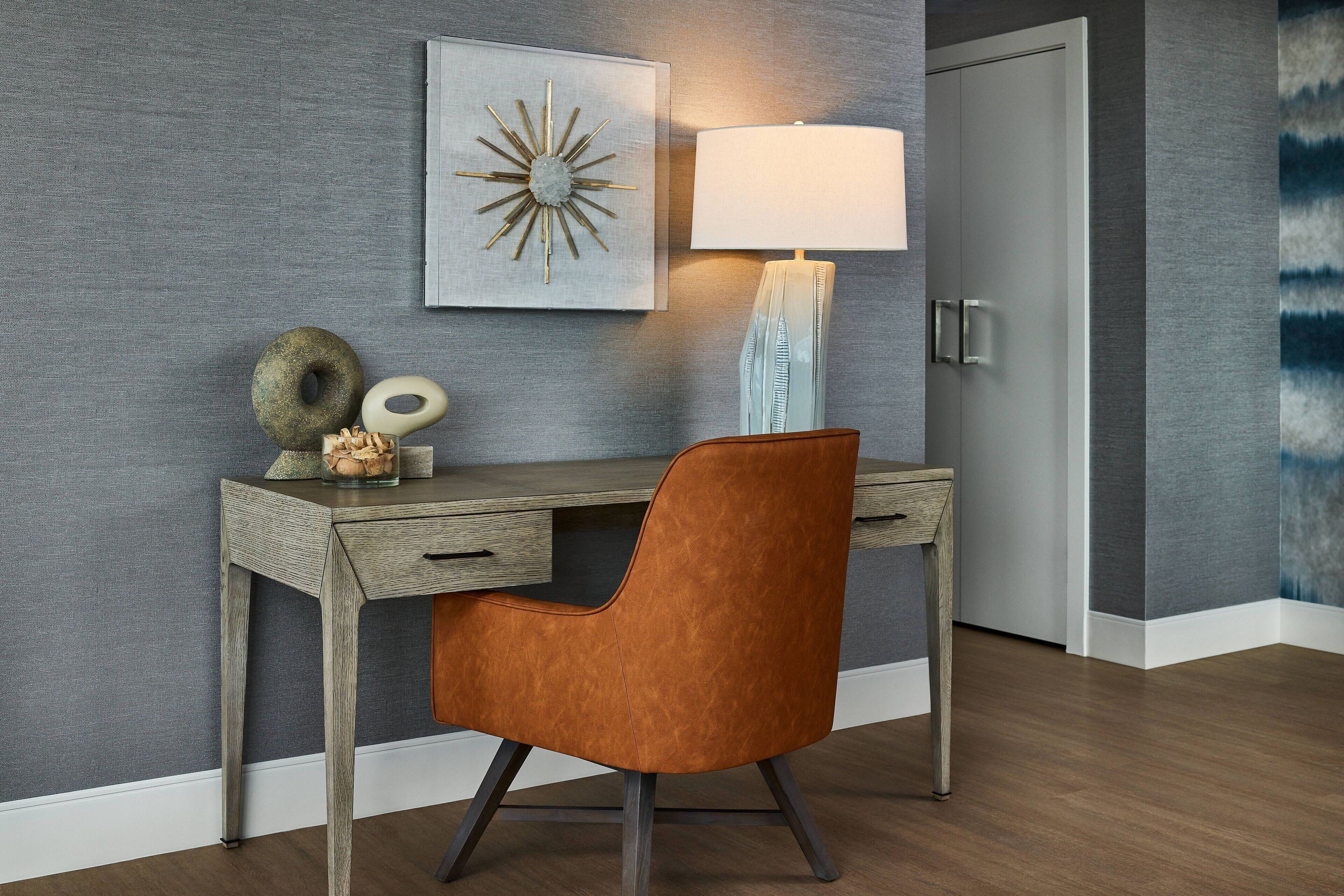A modern office space with a desk, chair, lamp, and decorative items.
