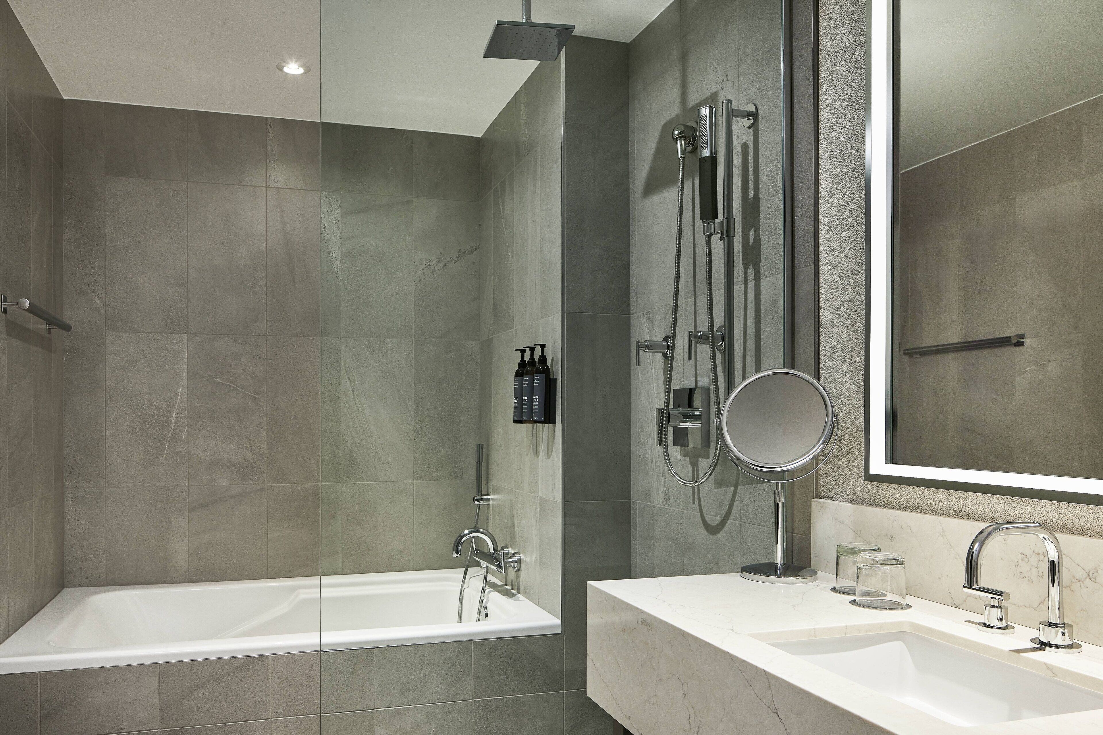A modern bathroom with a bathtub, a large mirror, and a sink with a faucet.