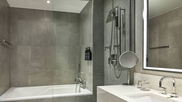 A modern bathroom with a bathtub, a large mirror, and a sink with a faucet.