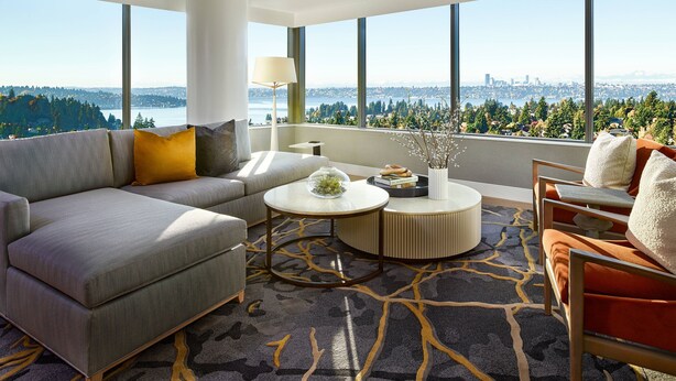 A modern living room with a gray sofa, a round coffee table, and a view of a cityscape through large windows. - The Westin Bellevue (Bellevue)