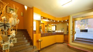 A hotel lobby with a reception desk, a staircase, and a decorative wall with animal figures. - Best Western Hotel Libertà (Modena)