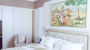 A bedroom with a large bed, a chair, a wardrobe, and a painting on the wall. - Best Western Hotel Libertà (Modena)