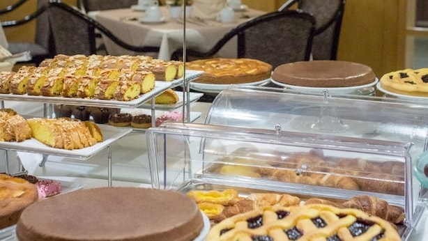 A buffet with various desserts displayed on glass stands. - Best Western Hotel Libertà (Modena)