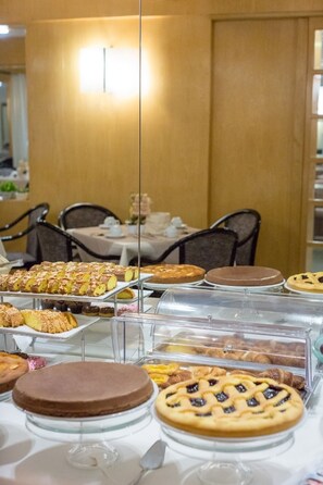 A buffet with various desserts displayed on glass stands. - Best Western Hotel Libertà (Modena)