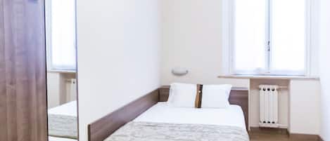 Een moderne slaapkamer met een houten bed, een nachtkastje, een grote spiegel en een raam met jaloezieën.