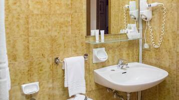 Bagno con bidet, lavandino, specchio e asciugacapelli montato a parete.