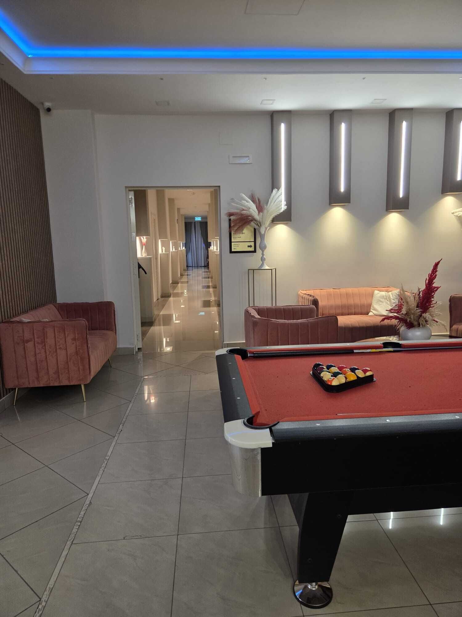 Un hall d’entrée moderne avec une table de billard, des canapés et un couloir menant à une autre pièce.