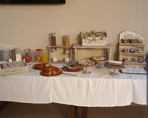Une table de buffet proposant une variété de plats, notamment des gâteaux, des pâtisseries et des condiments.