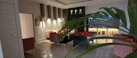 Un interior moderno con mesa de billar, sofá y una planta grande.