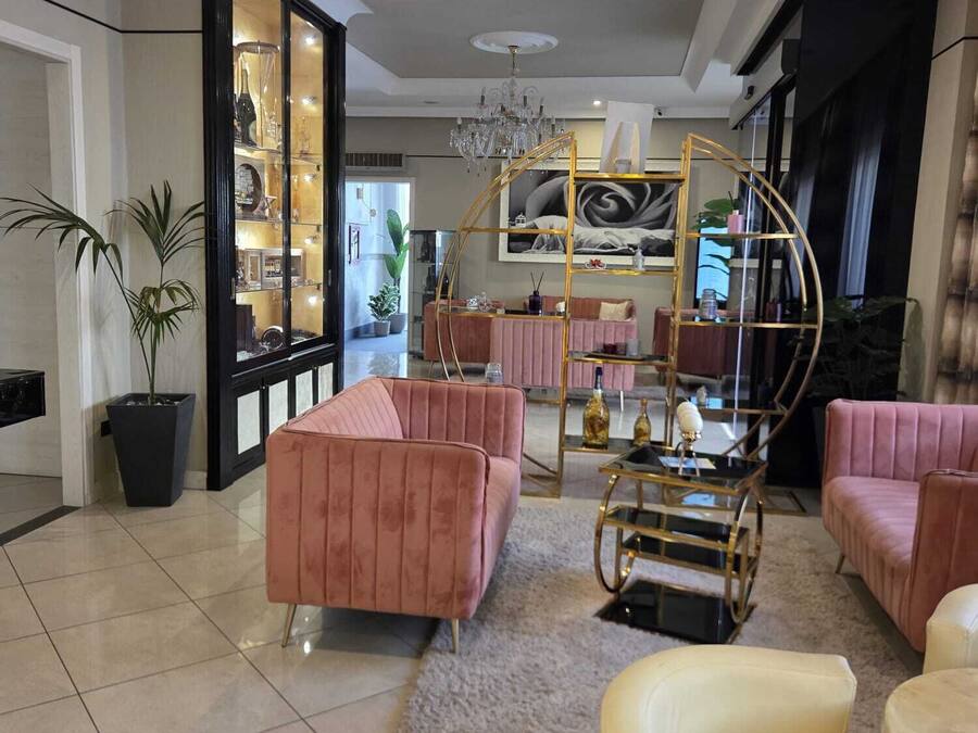 A spacious living area with a chandelier, pink sofas, a coffee table, and a large painting on the wall.