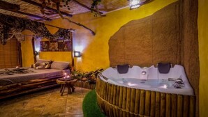 Une chambre avec un lit, une grande baignoire et une petite table avec des bougies.