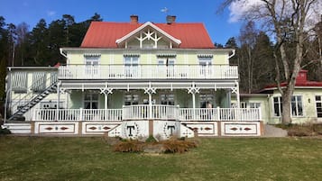 A two-story building with a red roof, white balconies, and a front porch.