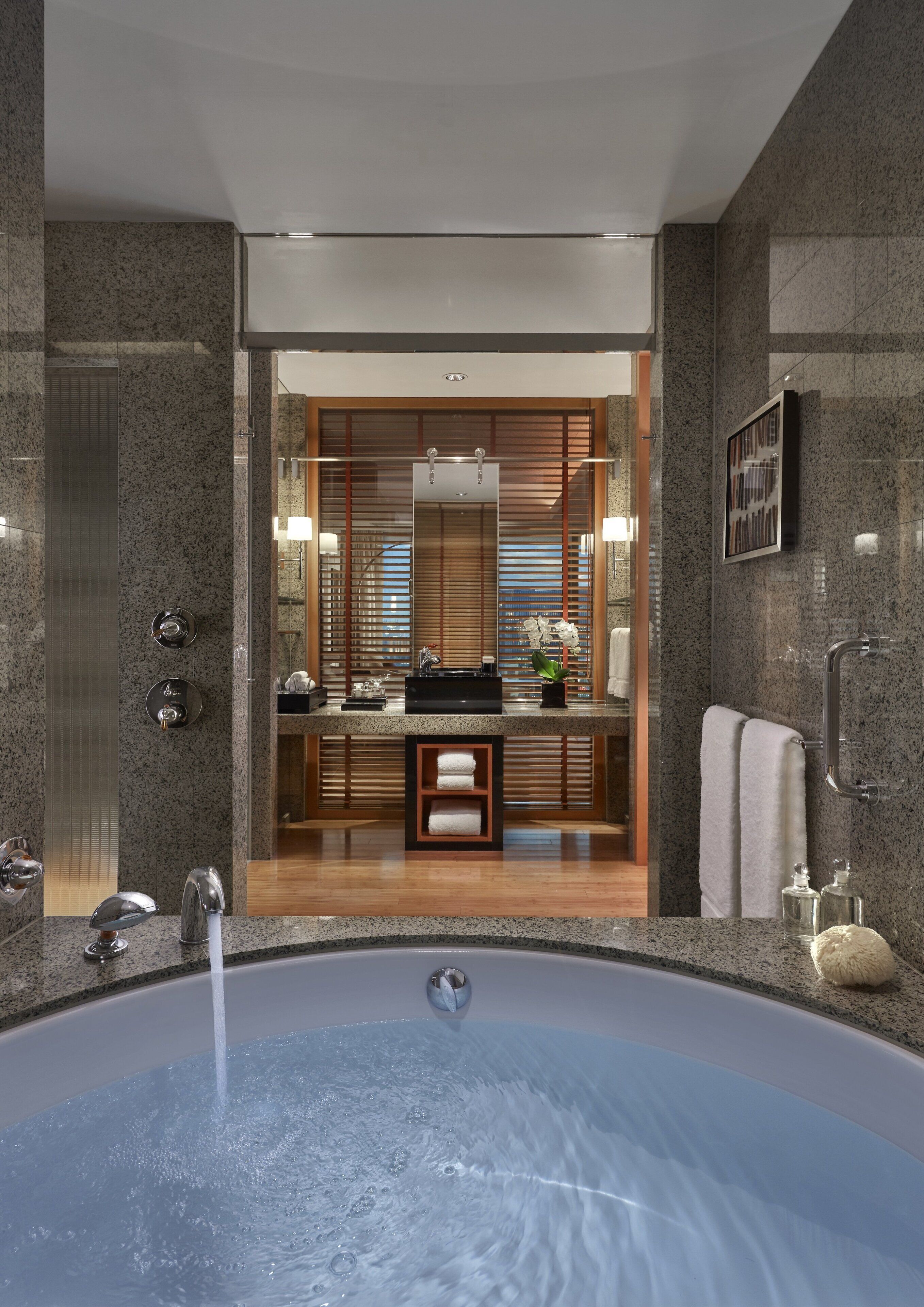 A modern bathroom with a large bathtub, a mirror, and a wooden vanity.