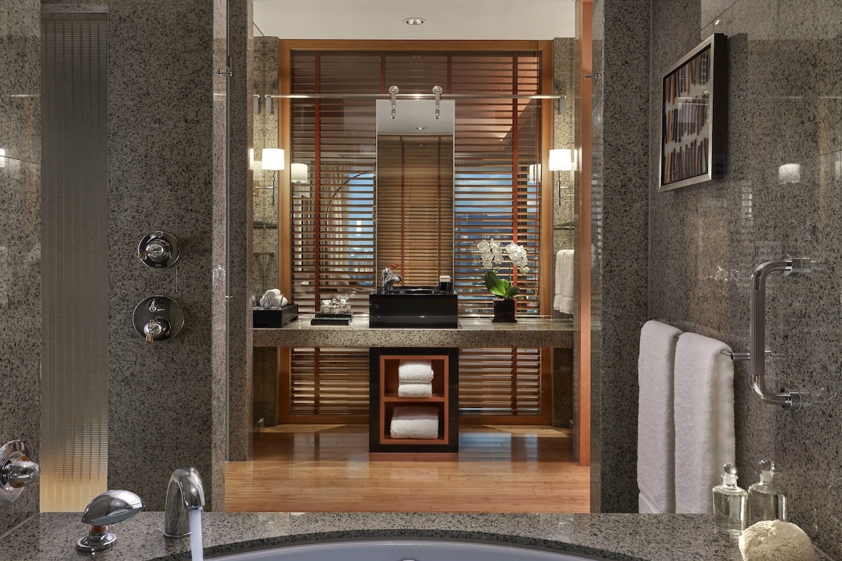 A modern bathroom with a large bathtub, a mirror, and a wooden vanity.
