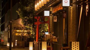 A street scene at night with a restaurant named 'Vinosity' and another named 'CREDO'. There are illuminated lanterns and a red torii gate.
