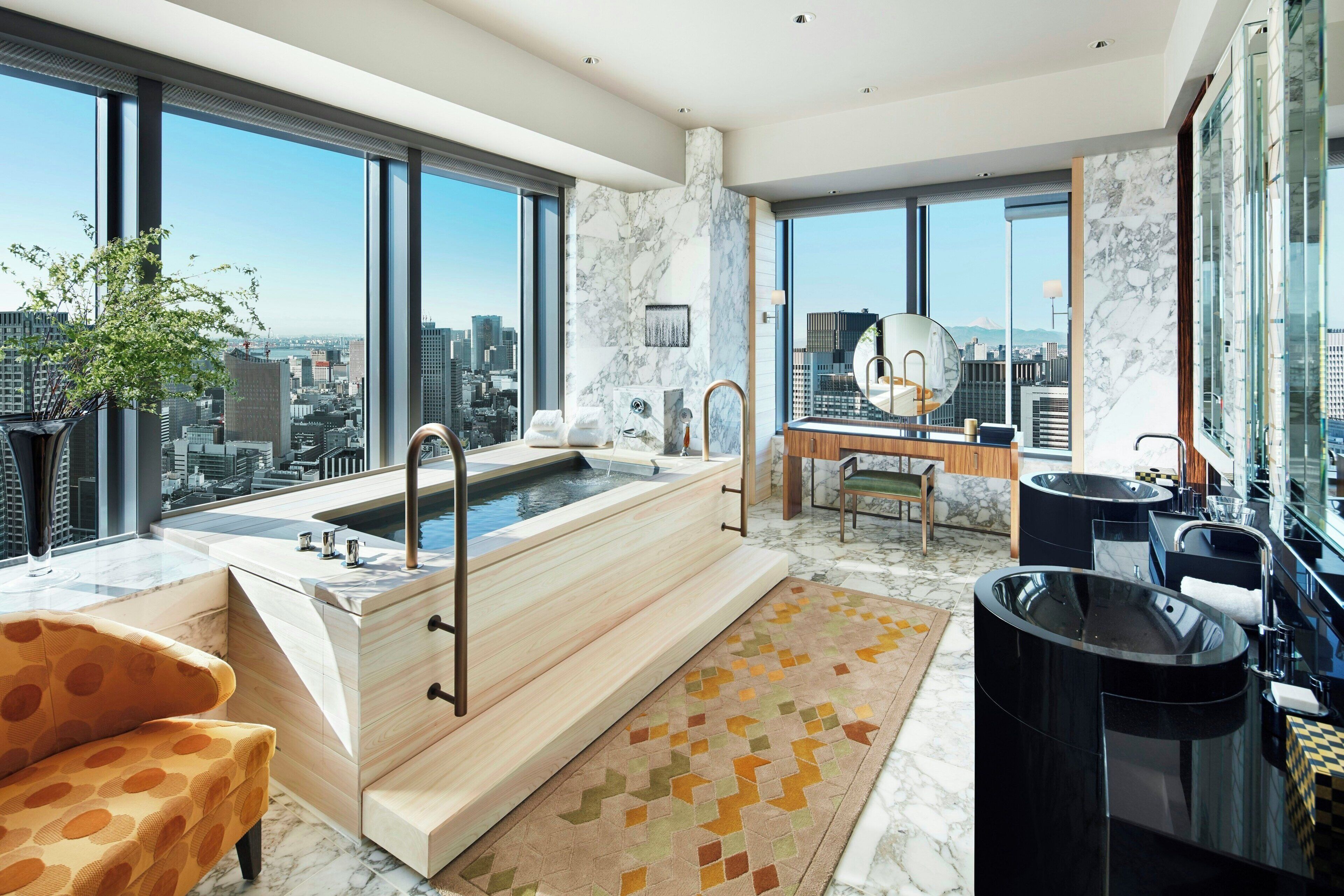 A modern bathroom with a large bathtub, a vanity, and a city view.