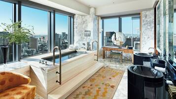 A modern bathroom with a large bathtub, a vanity, and a city view.