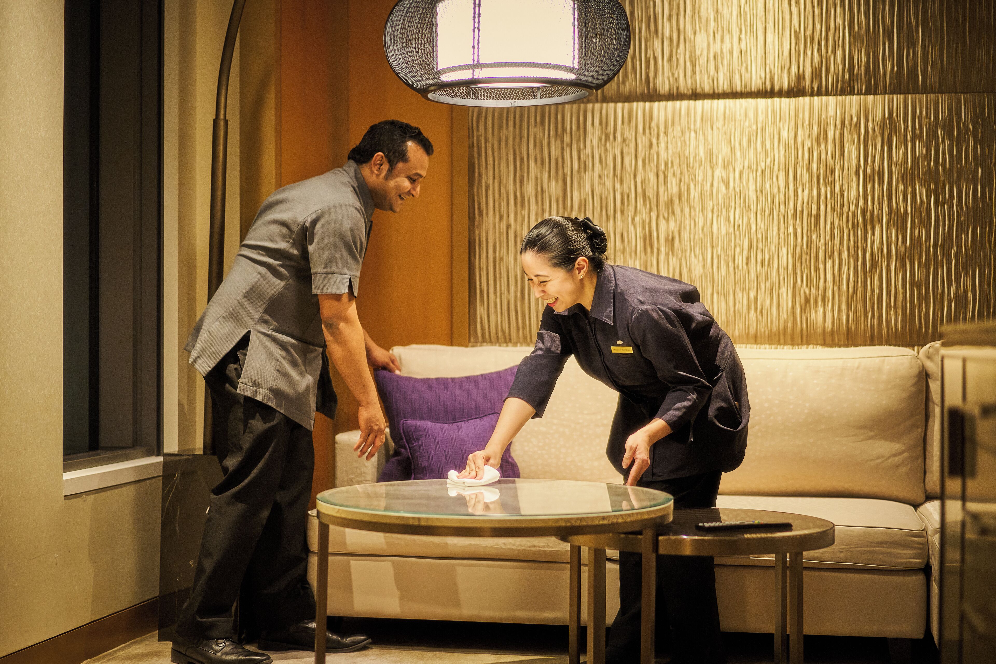 A hotel room with a sofa, a glass coffee table, and a round table.