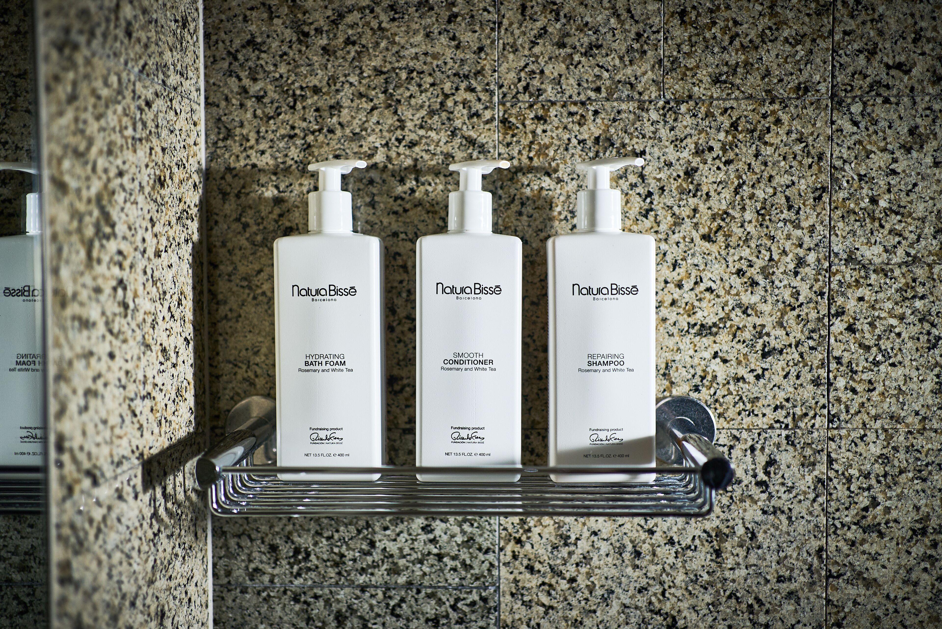 Trois produits Natura Bisse disposés sur un plan de travail en granit.