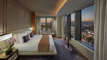 Ein modernes Hotelzimmer mit einem großen Bett, einem Fernseher und Blick auf die Stadt.