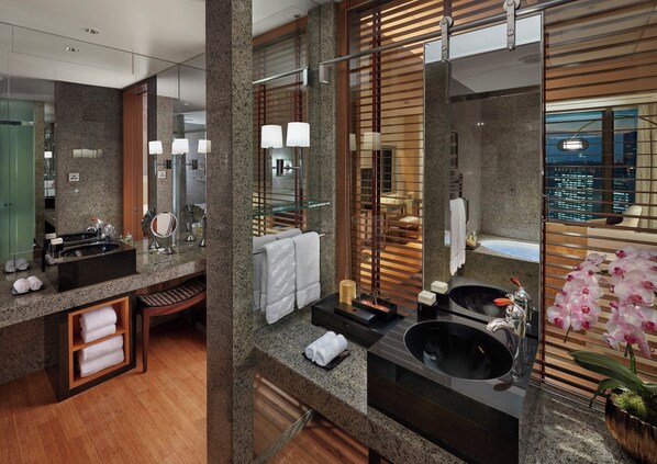 Un baño moderno con encimeras de granito, lavamanos dobles, un espejo grande y vistas a la ciudad.