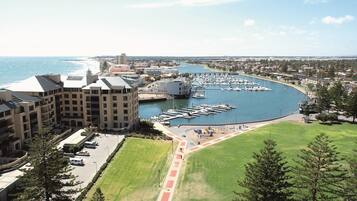 A coastal marina with boats, a parking lot, and a building with multiple floors.