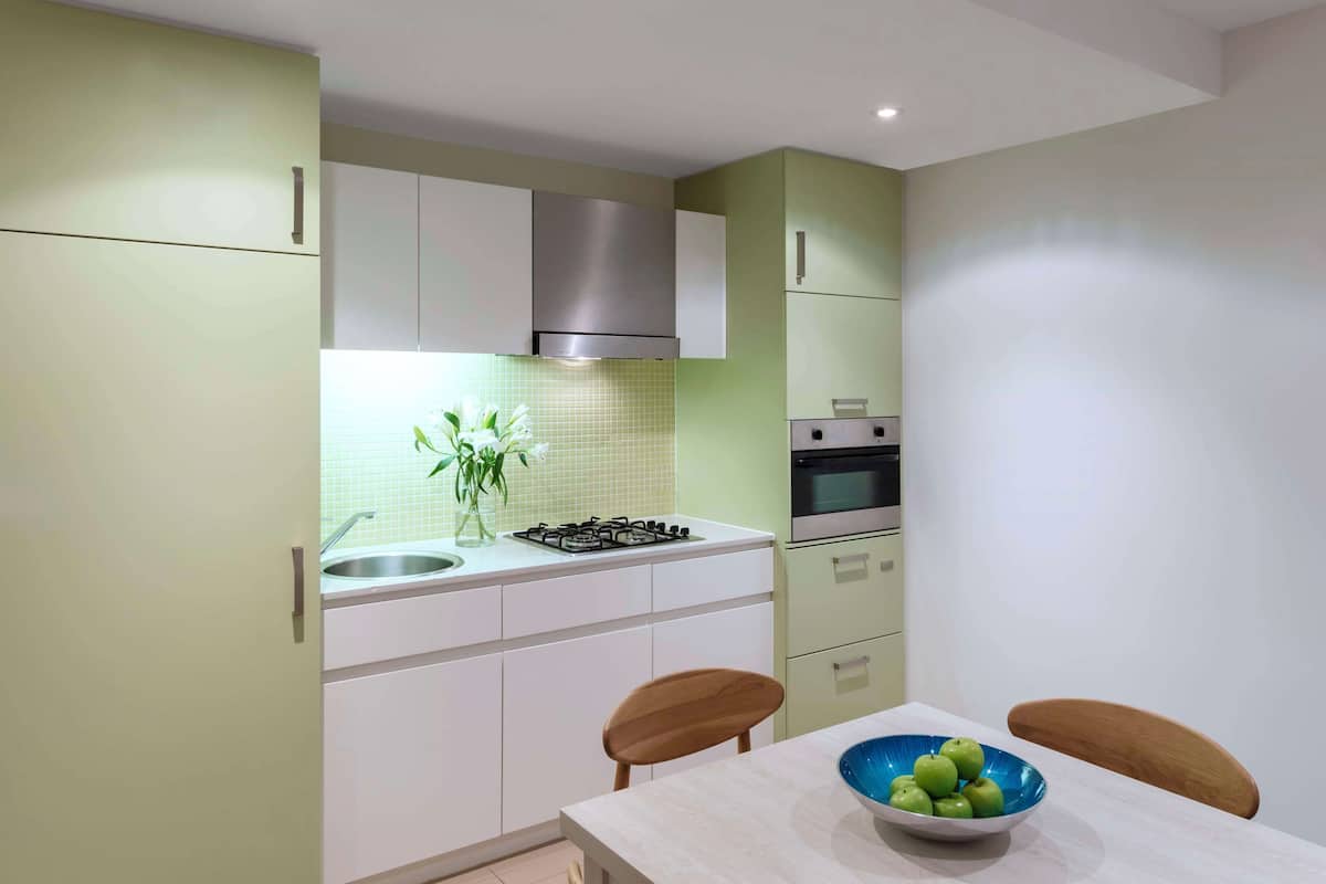 Une cuisine moderne avec des meubles blancs, une cuisinière à gaz, un évier et un coin repas comprenant une table et des chaises.