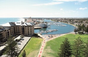 En småbåtshamn vid kusten med båtar, en parkeringsplats och en byggnad med flera våningar.