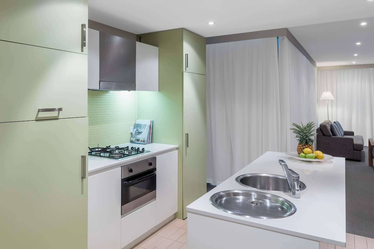 Une cuisine moderne avec des meubles blancs, un évier en acier inoxydable et une cuisinière à gaz.