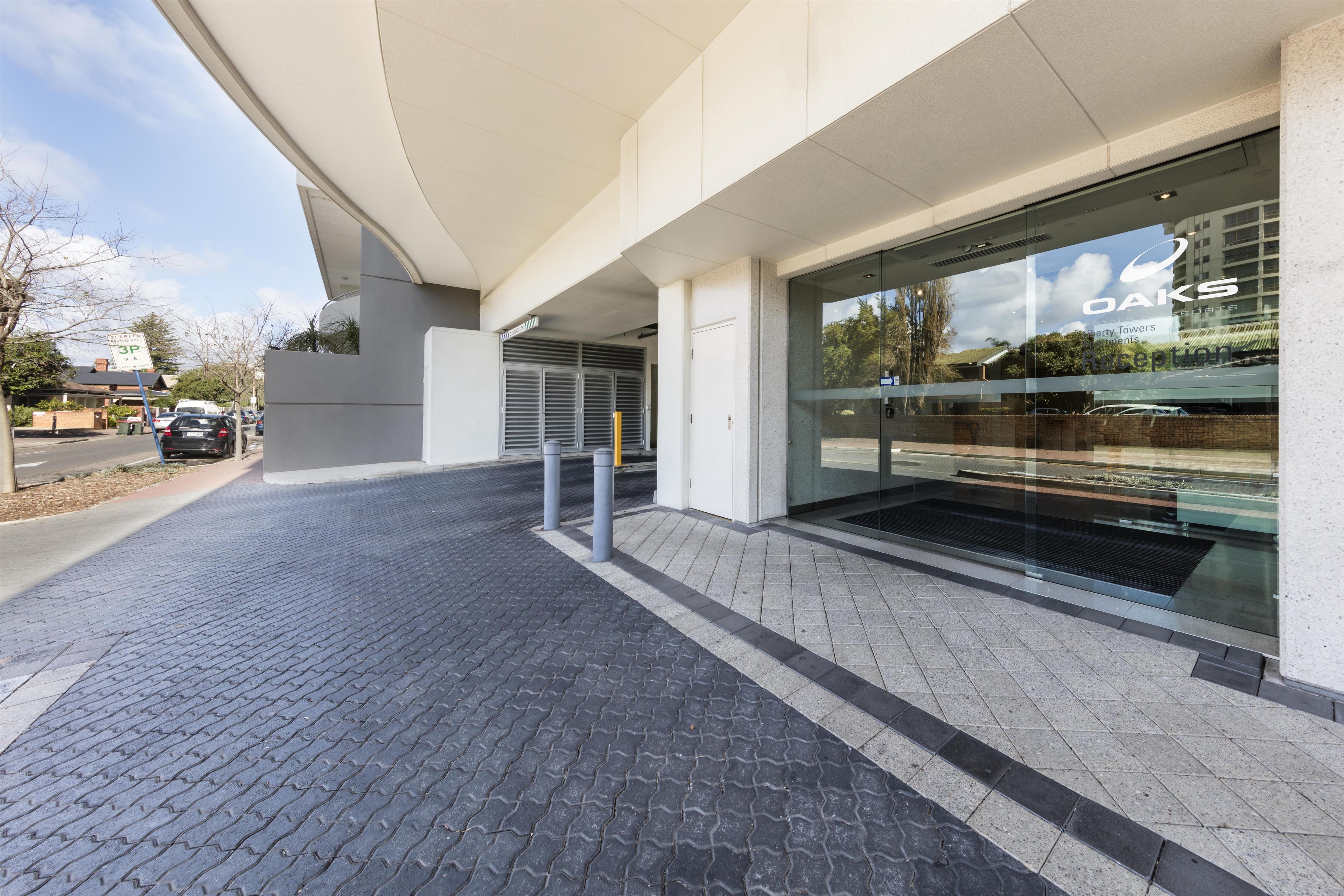 A modern building entrance with a paved driveway leading to a gated entrance.
