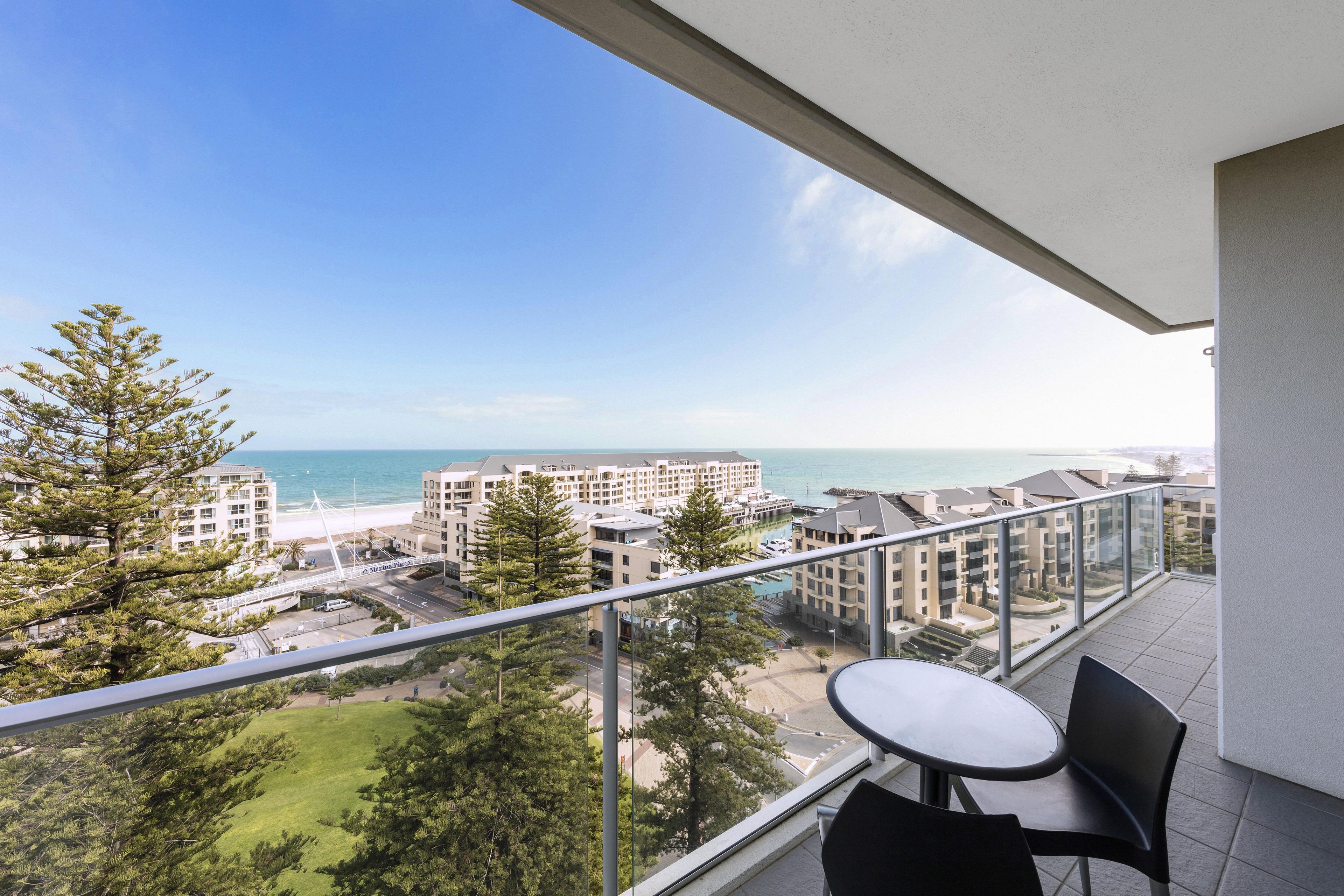 A balcony with a view of a beach, buildings, and a clear sky.