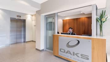 A reception desk with a logo, a man sitting behind it, and an elevator in the background.