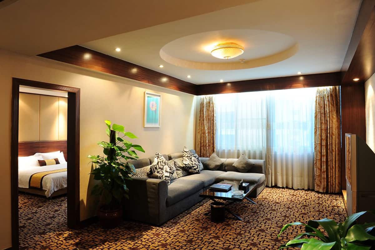 A hotel room with a bed, a sofa, a coffee table, and a large window with curtains.