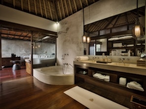 A modern bathroom with a large bathtub, a vanity with a mirror, and a wooden floor. - Hanging Gardens of Bali (Payangan)