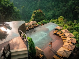Una piscina al aire libre, sombrillas, sillones reclinables de piscina