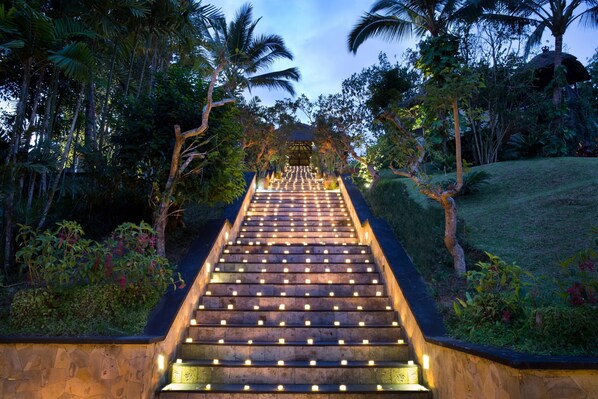 Eine Treppe mit Beleuchtung, umgeben von viel Grün und Palmen.