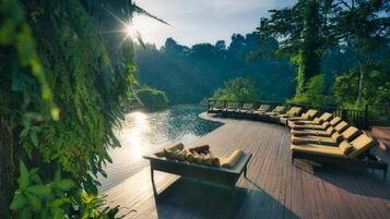 Una piscina al aire libre, sombrillas, sillones reclinables de piscina