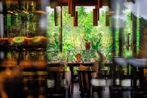 Un comedor interior con vistas a un jardín exuberante a través de amplios ventanales.