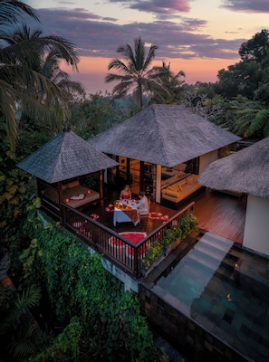 A resort with thatched-roof structures, a pool, and lush greenery.