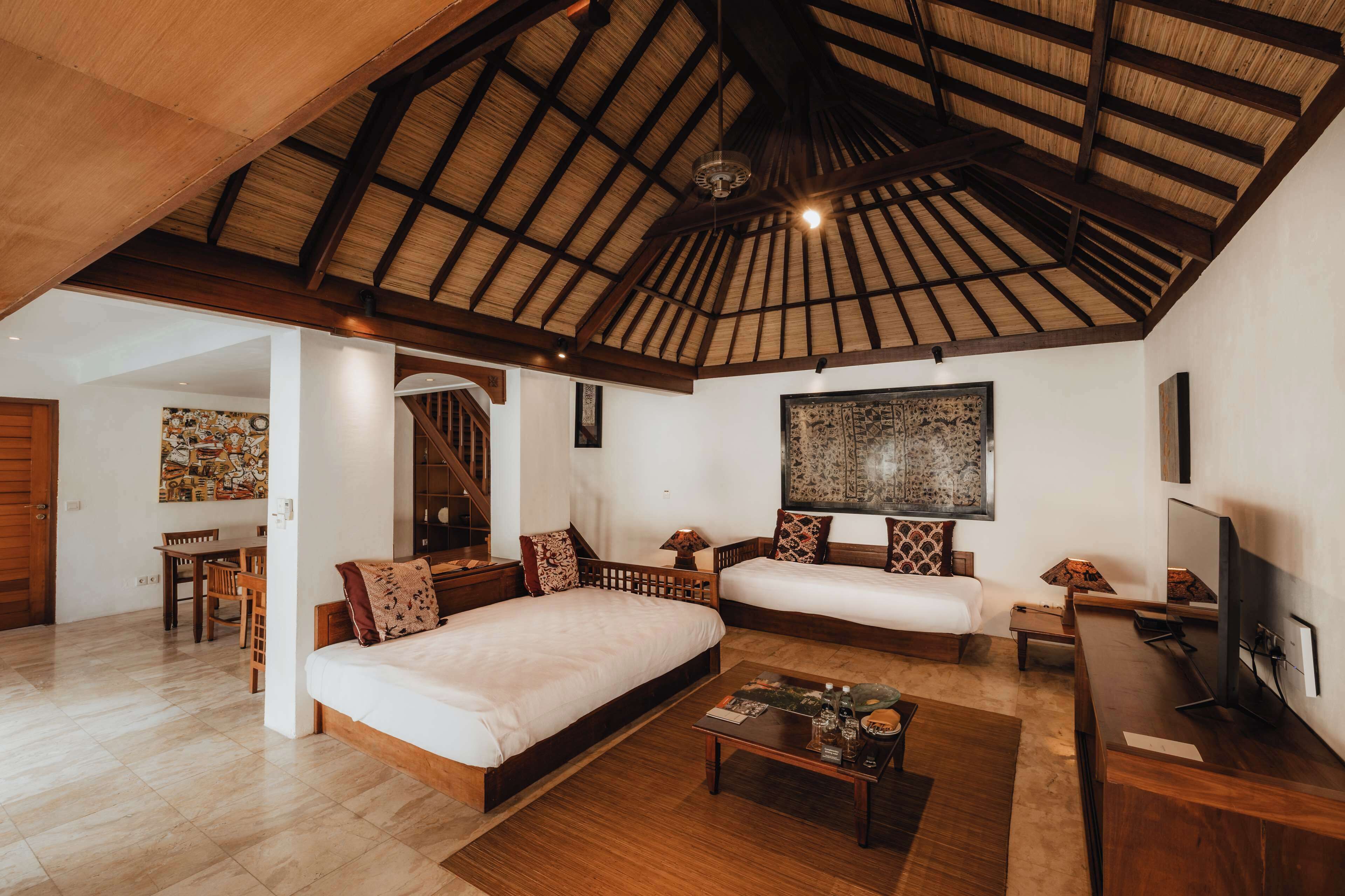 Una habitación amplia con dos camas, techo de madera y un comedor con mesa y sillas.